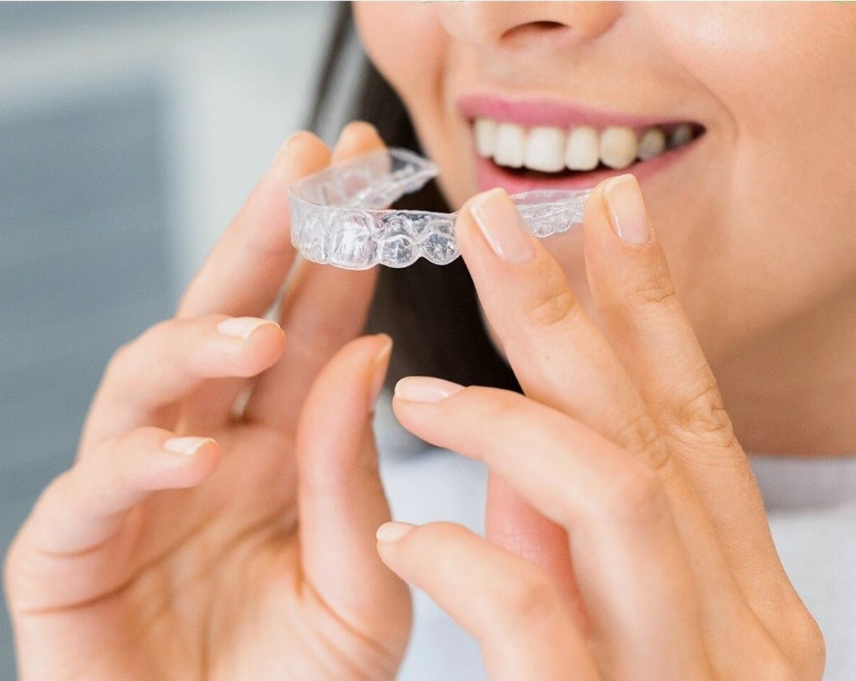 clear aligners Vashi patient holding Invisalign tray smiling at a dental clinic in Navi Mumbai